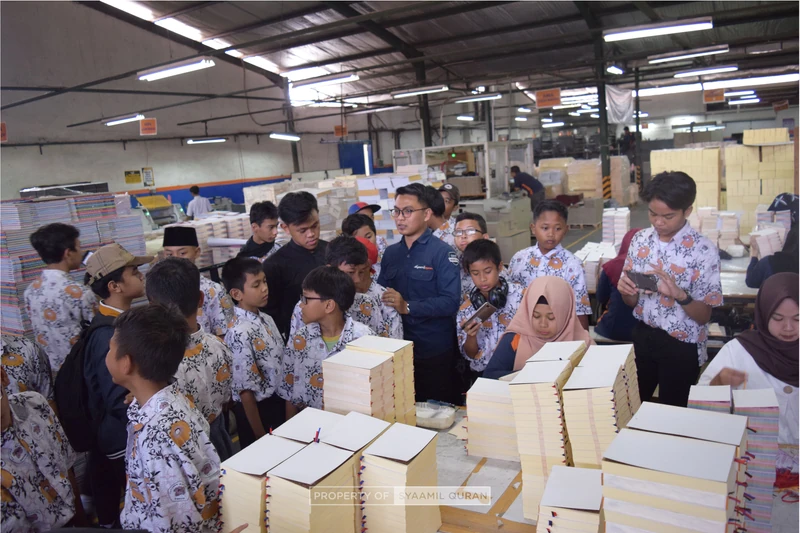 Students and a Syaamil guide learning about mushaf production inside the Qur’an printing factory.